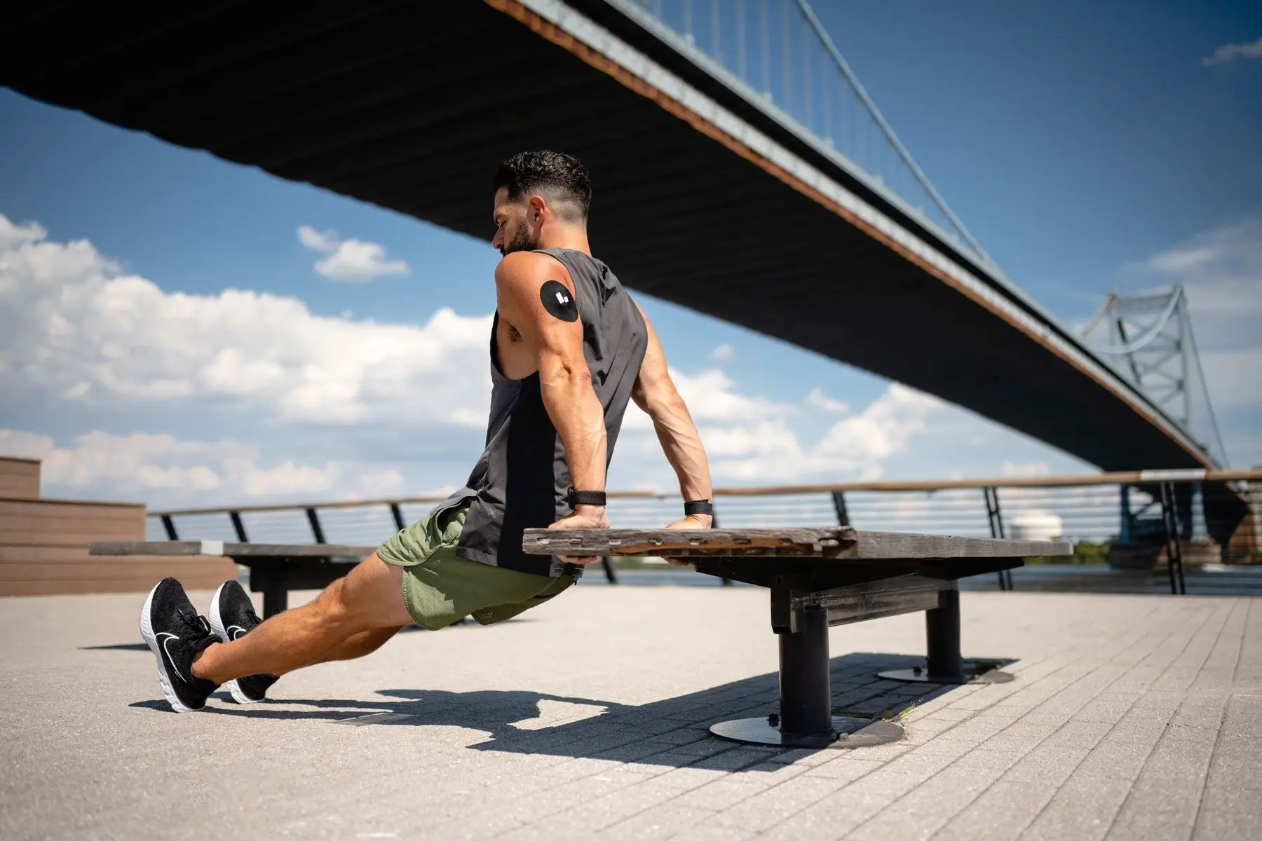 Man exercising on bench outdoor along a city riverside