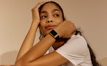 Woman in relaxed pose wearing a sleek WHOOP 4.0 fitness tracker, showcasing wellness technology as part of everyday style.