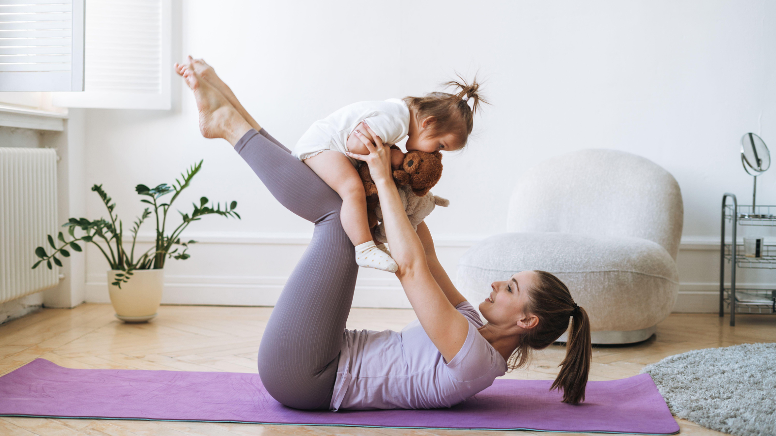 A woman doing yoga while holding a child